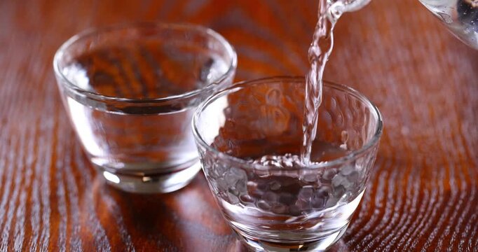 冷たい日本酒をガラスのお猪口に注ぐ