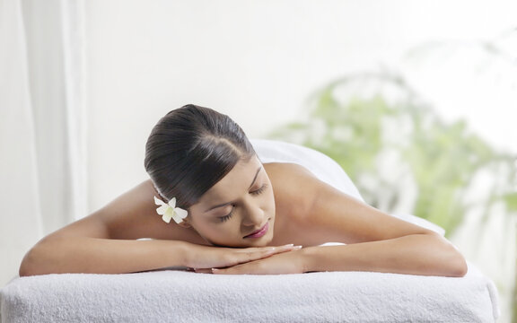 Pretty woman with eyes closed lying on message table 