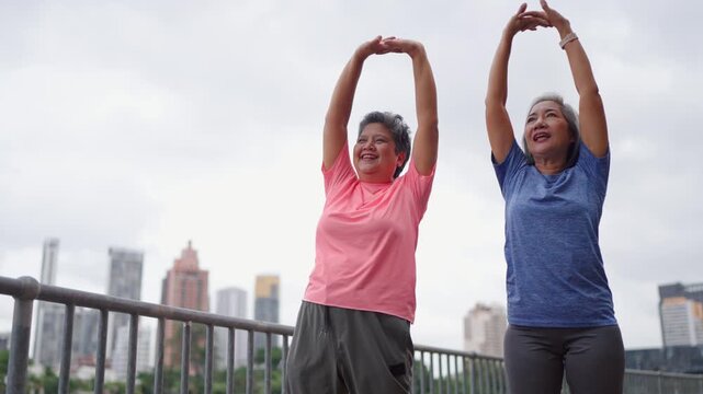 Two Asian senior women warm up body and exercise outdoor in modern city. 