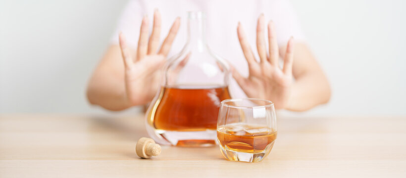 woman making stop hand gesture to refuse a glass of Cognac, Healthy man say no to alcohol drink, stop alcoholism and addiction concept. Responsible man reject a drink before driving and quit booze