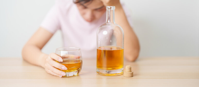 Stressed woman drinking whisky alone with problem. Exhausted drunk man looking stressed and sleepy. Alcohol addiction, Alcoholism, emotional distress and mental health concept