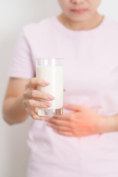 Lactose intolerance and Milk allergy concept. woman with Milk glass and having abdominal cramps and pain when drink Cow Milk. Symptom stomach ache, Dairy intolerant, Nausea, Bloating, Gas and Diarrhea