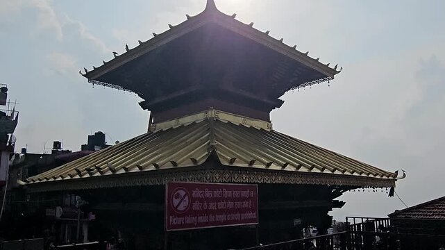 Footage of the historic Manakamana Temple in Nepal, showcasing its traditional multi-tiered pagoda-style architecture, ornate golden roof decorations, intricate wood carvings, and surrounding heritage