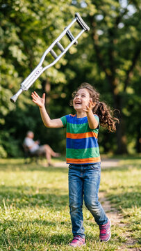 World Polio Day. Young girl who has defeated polio is happily playing with a crutch instead of a ball in a sunny park