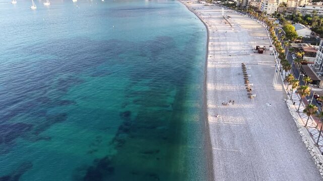 Aerial view of the sandy beach and palm-lined promenade along the turquoise Mediterranean sea in Altea, Valencian Community, Spain.