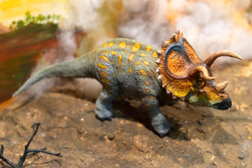 Miniature diorama of a horned Triceratops dinosaur model in a natural museum display. © wannasak