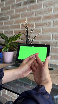 Woman attending online therapy session on a laptop with a green screen, showing anxiety by wringing her hands, seeking mental health support and professional help