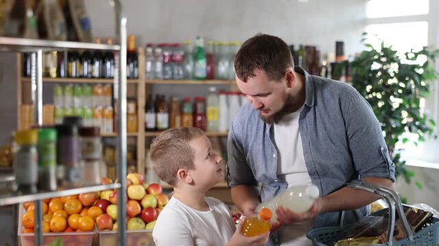Father and son boy in store scans QR code on carbonated beverage bottle. With help of mobile app, buyers receive information about product. They checks product in registry database of national agency
