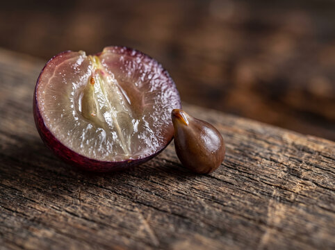 Half sliced red grape showing inner juicy pulp on rustic table