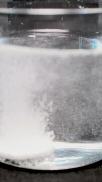 Close-up macro video of numerous bubbles forming and rising through a clear liquid during an effervescent reaction, creating an abstract sparkling texture. Suitable for science, chemistry, hydration, 