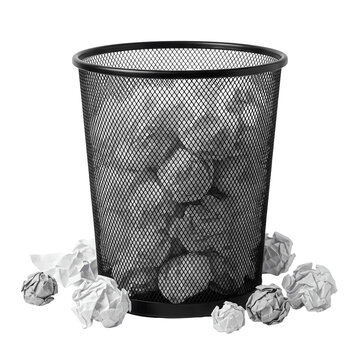 Black mesh wastebasket full of crumpled paper, with more discarded paper around it, isolated on white background