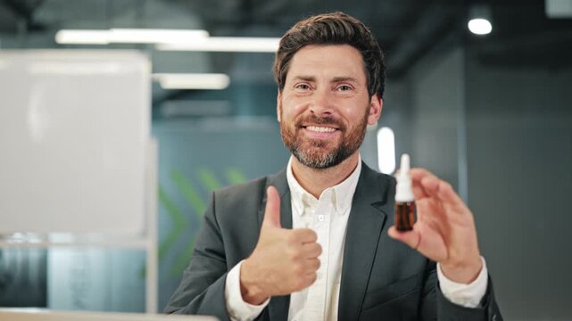Professional man endorses small bottle product. Confident expression, gives thumbs-up for approval. Represents health, wellness, and business concepts. Suitable for medical, pharmaceutical