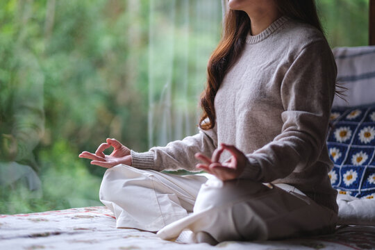Closeup of a woman meditating or practicing yoga in lotus pose on the bed
