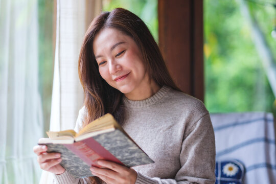 Portrait image of a woman reading a book at home