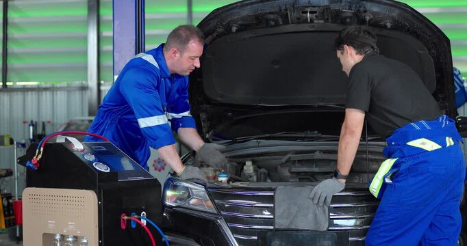  Auto mechanics servicing electric car air conditioning system with refrigerant recharge machine