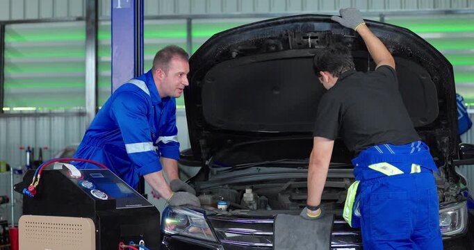 Auto mechanics servicing electric car air conditioning system with refrigerant recharge machine