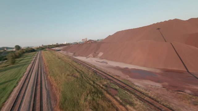 FPV drone weaves low over CN ore dock as taconite pellets load onto lake freighter along railroad tracks in Duluth Minnesota at sunset