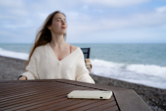 Woman enjoying a peaceful moment by the ocean without her phone. Slow living, digital detox and mindful seaside relaxation in cool weather.