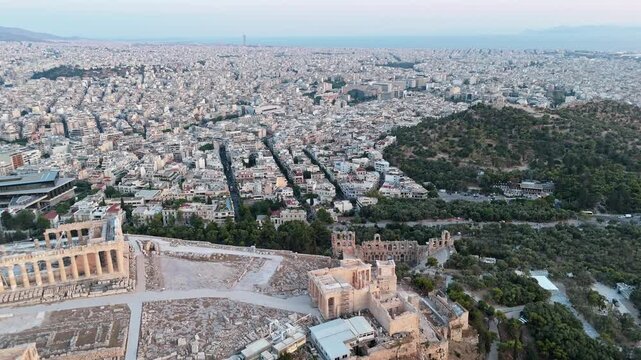 Acropolis of Athens with the Odeon of Herodes Atticus sits above sprawling neighborhoods with the Saronic Gulf in the distance.