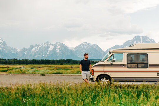 Man on road trip with vintage van in mountains
