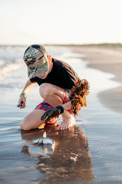 Young boy examines a freshly caught fish on beach