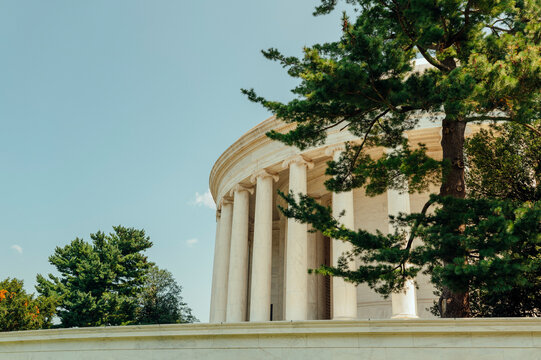 Classical memorial framed by trees beneath a clear blue sky.