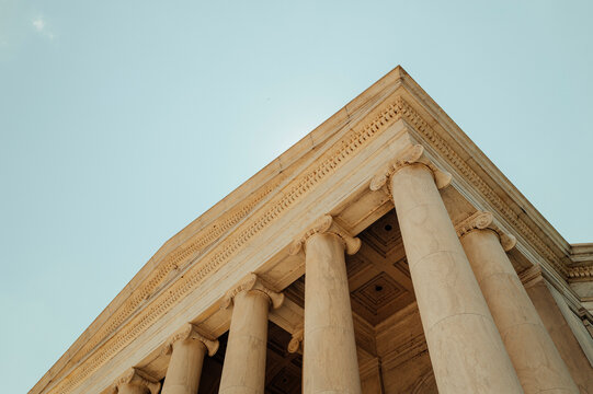 Low angle view of classical columns against blue sky.