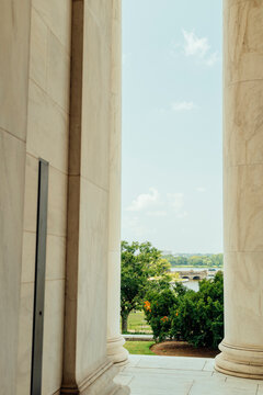 View through towering marble columns toward a summer landscape.