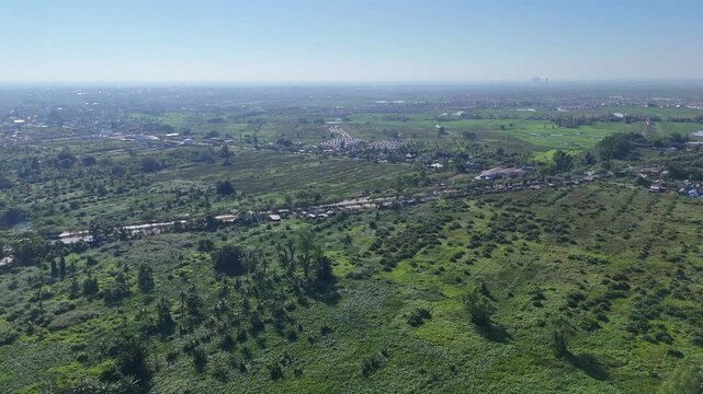 Aerial view of TPA Basirih landfill site surrounded by lush green vegetation and rural landscape in Kecamatan Banjarmasin Selatan, Kalimantan Selatan, Indonesia.