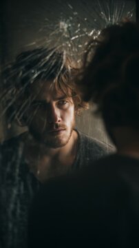 Reflective portrait of a man gazing into a shattered mirror capturing feelings of introspection and vulnerability in an artistic composition. Generative AI