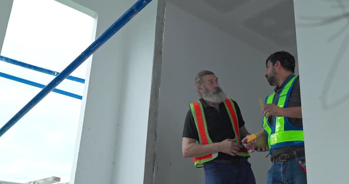 Construction worker measuring window opening with tape measure at house building site