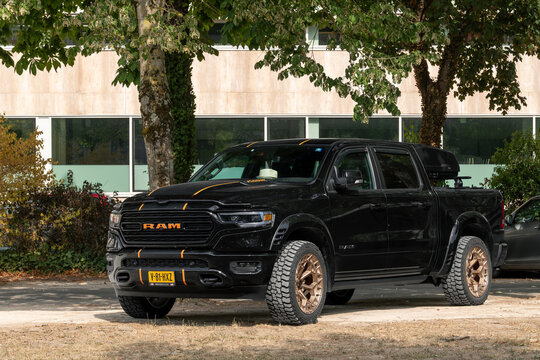 Nancy, France - August 15th 2026 : View on a black Dodge Ram 1500 parked on a street with vegetation and buildings in the background.