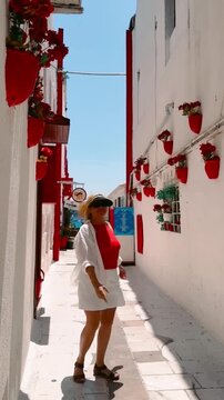Smiling female tourist enjoying a walk through historic streets of Bodrum Old Town, Turkey. White buildings, colorful flower pots and charming architecture make this famous Aegean resort a popular
