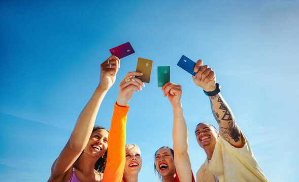 Young adults raise credit cards outdoors celebrating student financing