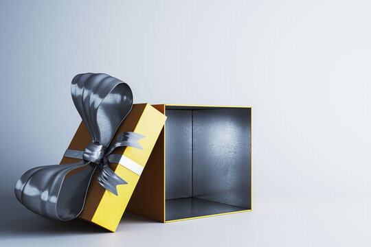 Open gift box with dramatic black ribbon and yellow geometric wrapping, isolated on a light white background for contemporary presentation design. 3D Rendering