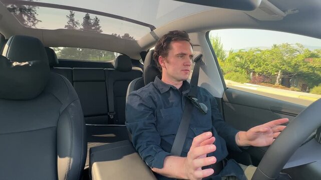 Man raises his hands off the wheel in mock surprise as his electric vehicle drives itself hands-free on autopilot.