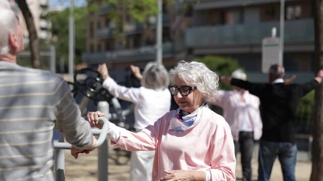 Elderly men and women gather in courtyard, using outdoor gym equipment for fitness