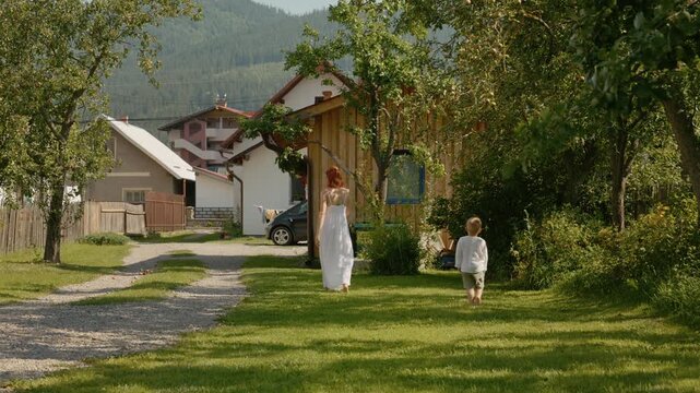 A woman and her little boy spend time in their yard. They run and play together while enjoying the sunshine and fresh air in their neighborhood.
