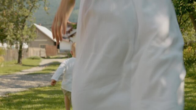 A woman and her little boy run and play in their yard. They laugh and share fun moments. The sun shines as they enjoy their family time together outside.