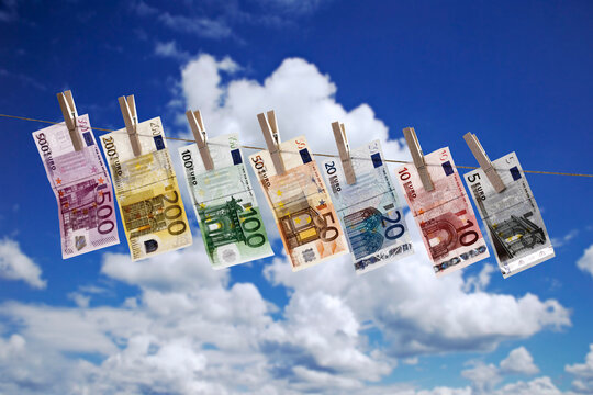 Different Euro bank notes hanging on clothesline against cloudy sky
