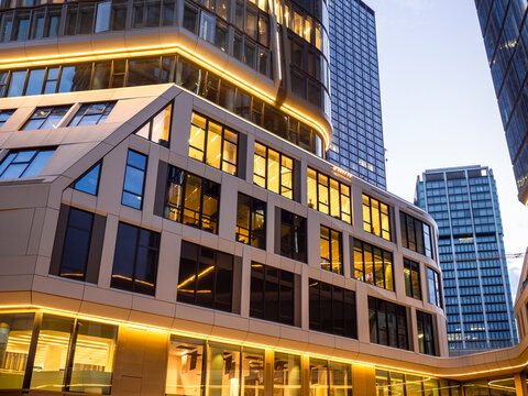 Illuminated modern office building in Frankfurt skyline at evening