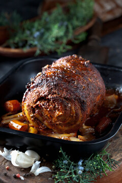 Rolled roast pork with braised vegetables in a pan indoors