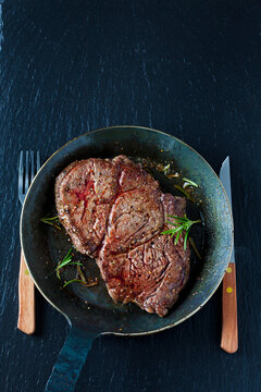 Rib eye steak with rosmary in frying pan