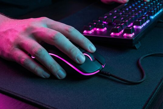 Gamer hand clicking on illuminated RGB gaming mouse