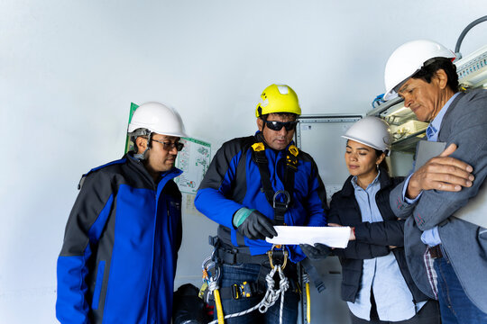 A technician checks a corporate document at a wind turbine base