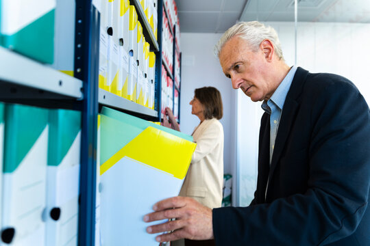 Businessman and businesswoman search for a document in the archive