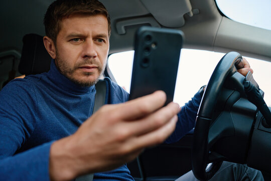 Man Using Smartphone While Sitting in Car Before Driving