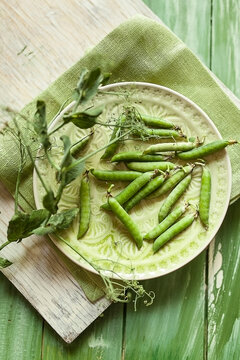 Bowl of peapods, Pisum sativum, on cloth and wood
