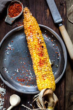 Grilled corncob with butter, salt and chili flakes on plate