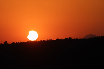 Partial Solar Eclipse Sunset Over Distant Tree Horizon © JoseAngel